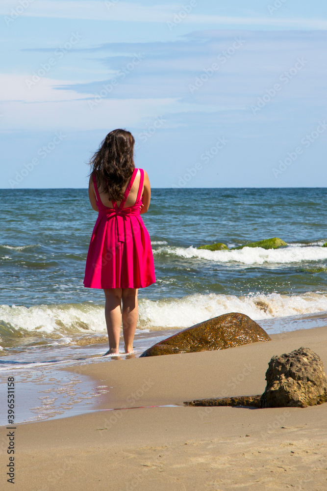girl in a scarlet dress by the sea. Wind, waves, deserted beach