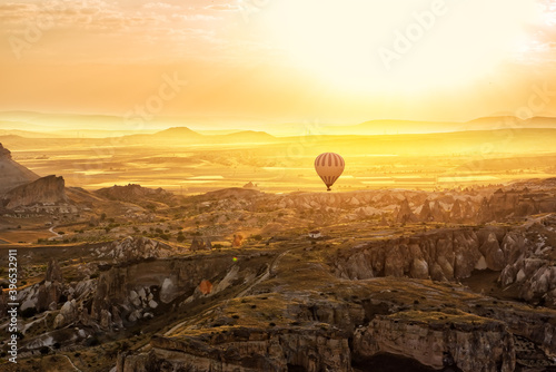 Fantastic sunrise in a valley with rocks and a hot air balloon against the backdrop of a dramatic sky. View from a height of the rock massifs. Cappadocia. Turkey.