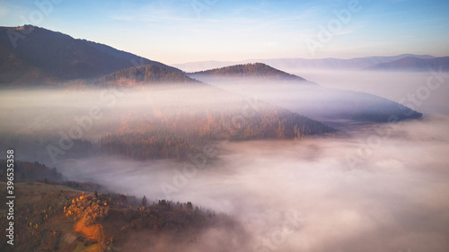 Beautiful Autumn mountain panorama. Morning thick fog cover valley aerial view. Fantastic fall sunrise