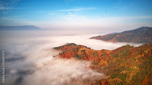 Obraz na płótnie Beautiful Autumn mountain panorama. Morning thick fog cover valley. Sunny landscape with meadow and colorful forest w salonie