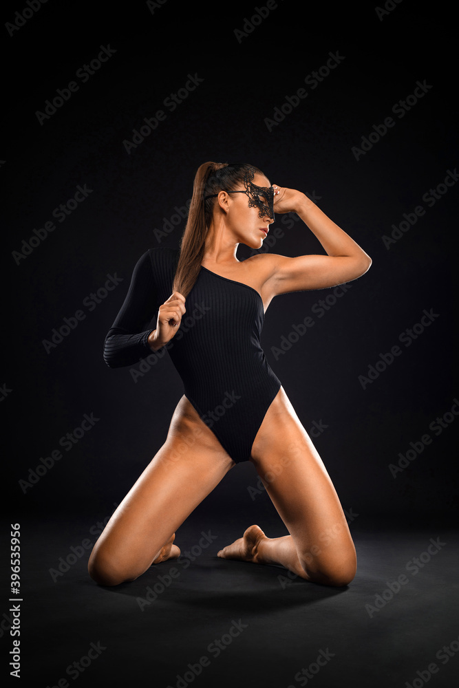 Fototapeta premium Sexy young woman in bodysuit and mask on black background