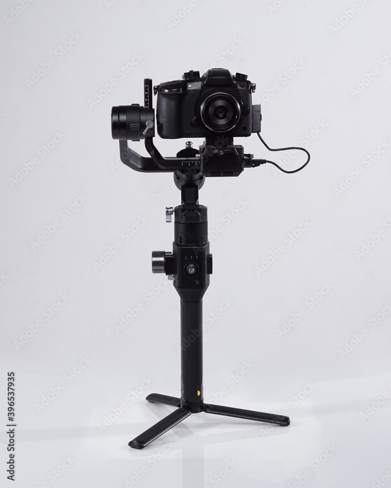 Mirrorles professional cameras with a gimbal camera stabilizer. Video Camera Gimbal Stabilization Tripod System on a white background. Gimbals Stabilization System with Mirrorless Camera.