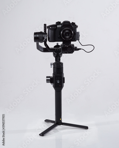 Mirrorles professional cameras with a gimbal camera stabilizer. Video Camera Gimbal Stabilization Tripod System on a white background. Gimbals Stabilization System with Mirrorless Camera. photo