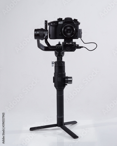 Mirrorles professional cameras with a gimbal camera stabilizer. Video Camera Gimbal Stabilization Tripod System on a white background. Gimbals Stabilization System with Mirrorless Camera.