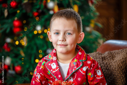  Little boy in red christmas pajamas sitting near the christmas tree