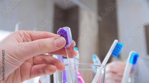 Changing toothbrush. Female hand replacing old dirty worn out tooth brush with a new one. Closeup, slow motion. Shot in 60 fps, slowed down to 24 fps.