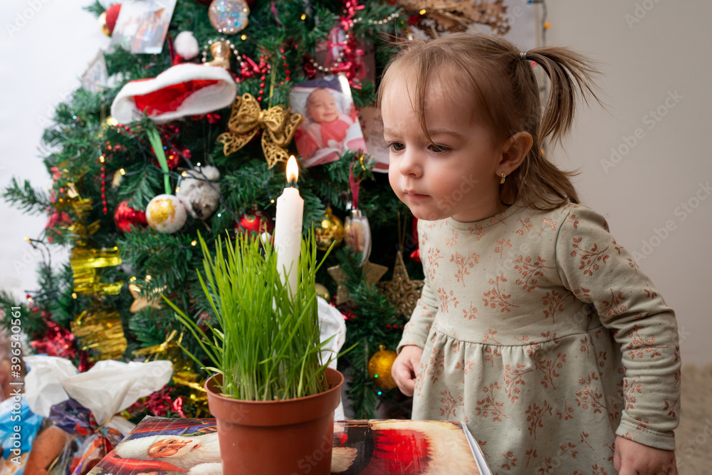 Little girl playing next to Christmas tree, dancing, singing and making a secret sweet  wishes to send to Santa