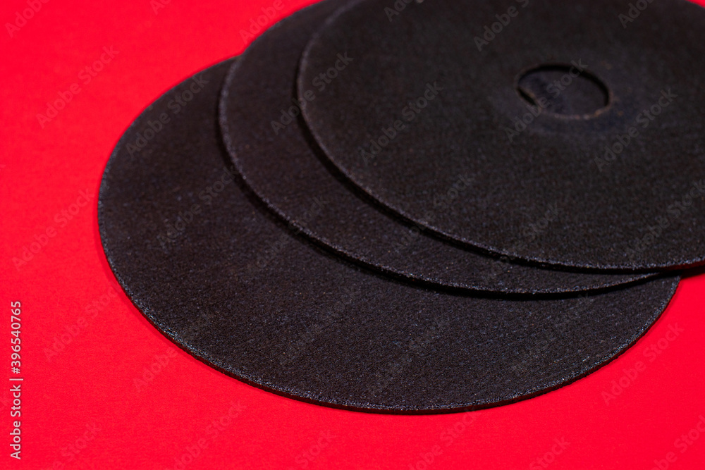 A cut-off wheel for a grinder tool on a red background with a place for copyspace text. Tools for construction and repair, workshop.