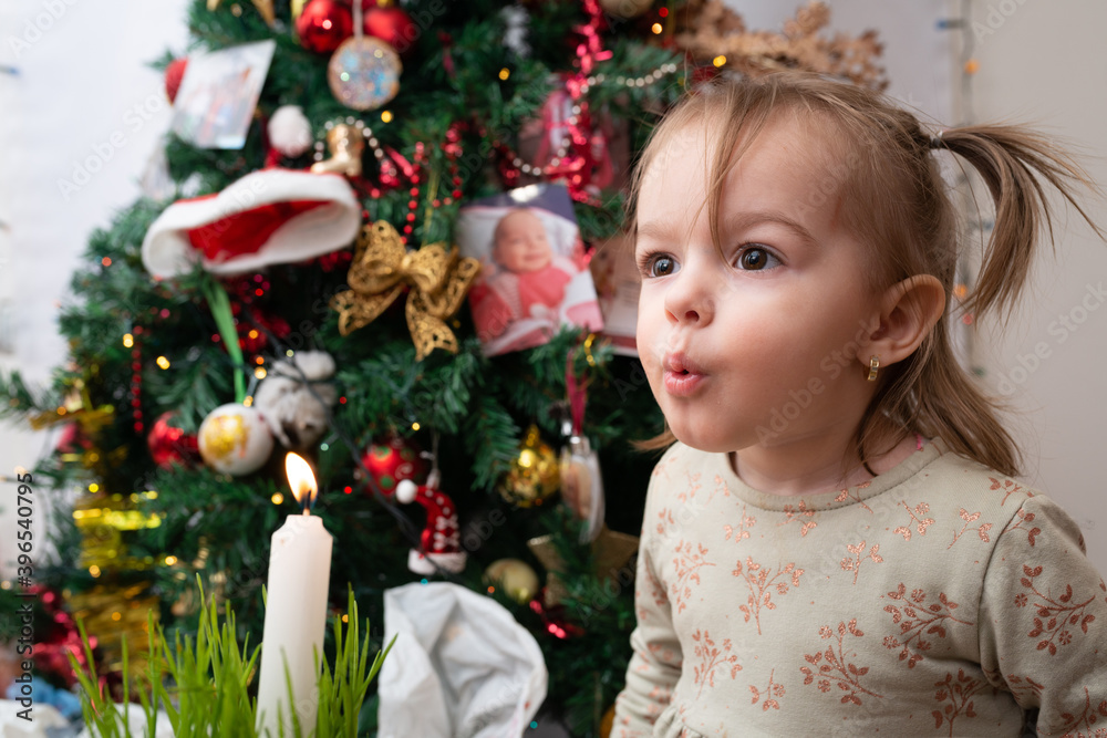 Little girl playing next to Christmas tree, dancing, singing and making a secret sweet  wishes to send to Santa