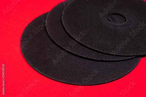 A cut-off wheel for a grinder tool on a red background with a place for copyspace text. Tools for construction and repair, workshop.