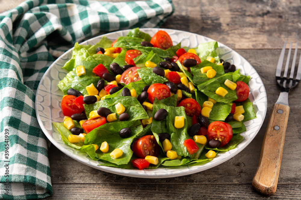 Mexican salad with black beans, corn,tomatoes,lettuce and pepper on wooden table