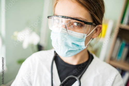 Close up face of young medical doctor wearing protective face mask and glasses and stethoscope standing in the hospital