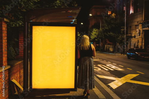 Illuminated blank billboard with copy space for your text message or content with woman standing by billboard © bennian_1
