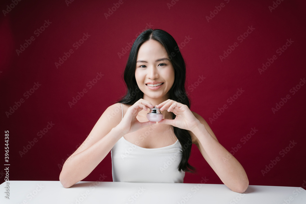 Portrait of beautiful lady holding a cosmetic jar of cream isolated on red background. Portrait of beautiful lady holding a cosmetic jar of cream isolated on red background.