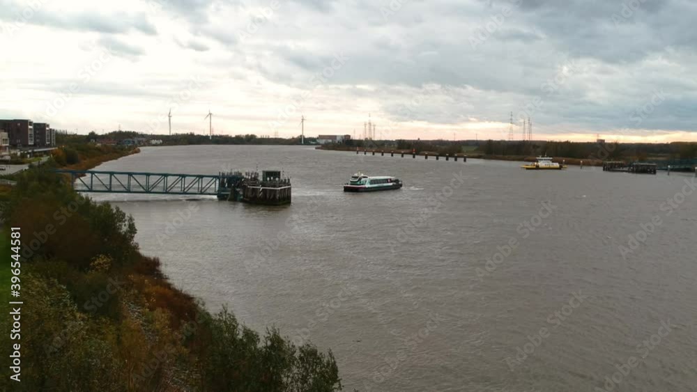 Drone pulls back over a river with a ferry with a grey overcast horizon Drone pulls back over a river with a ferry with a grey overcast horizon