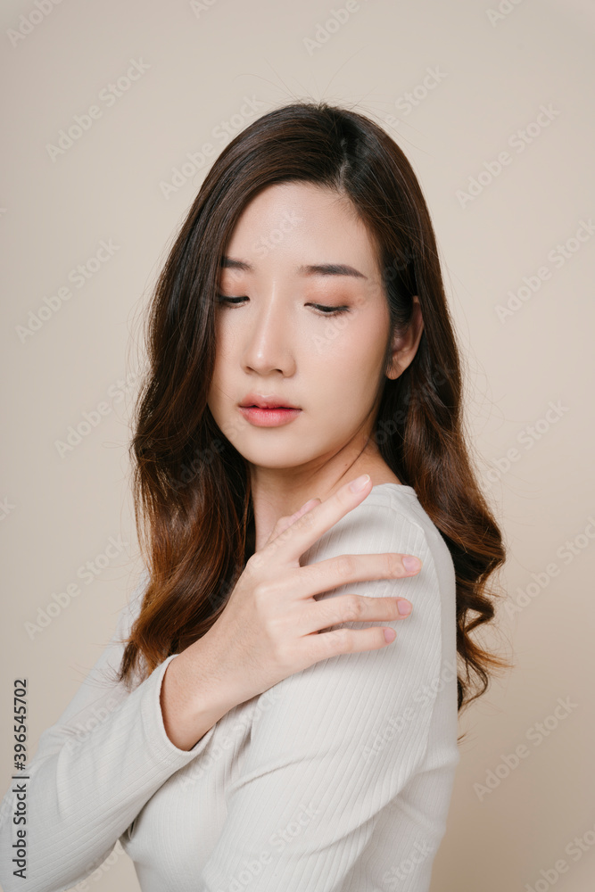 Portrait of beautiful asian woman touching shoulder isolate on beige. Portrait of beautiful asian woman touching shoulder isolate on beige.