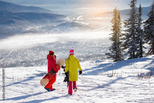 Two Woman snowboarders walks on the snowy mountain.