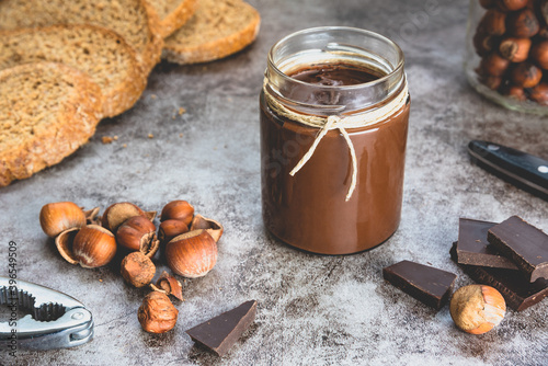 Homemade hazelnut chocolate butter, hazelnut, dark chocolate, on black stone background.