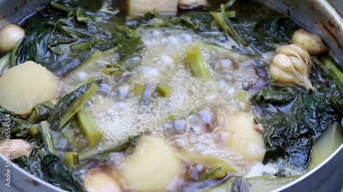 Vegetable soup in a pot with boiling and smoke.