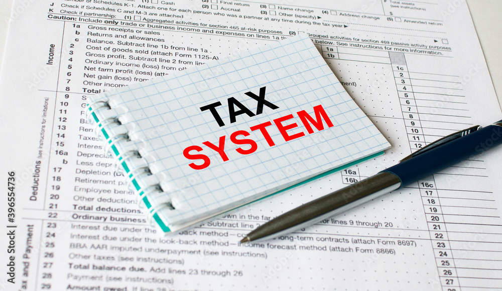 Fototapeta premium Notepad with text Tax System lying on financial tables with a pen