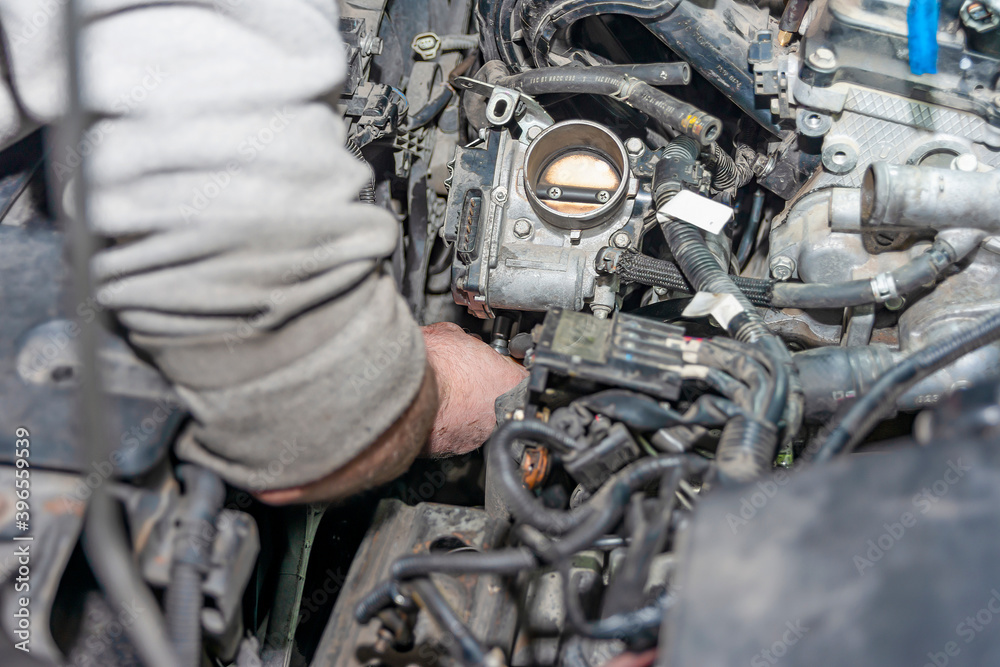 A young man attaches the throttle bodies to the engine.
