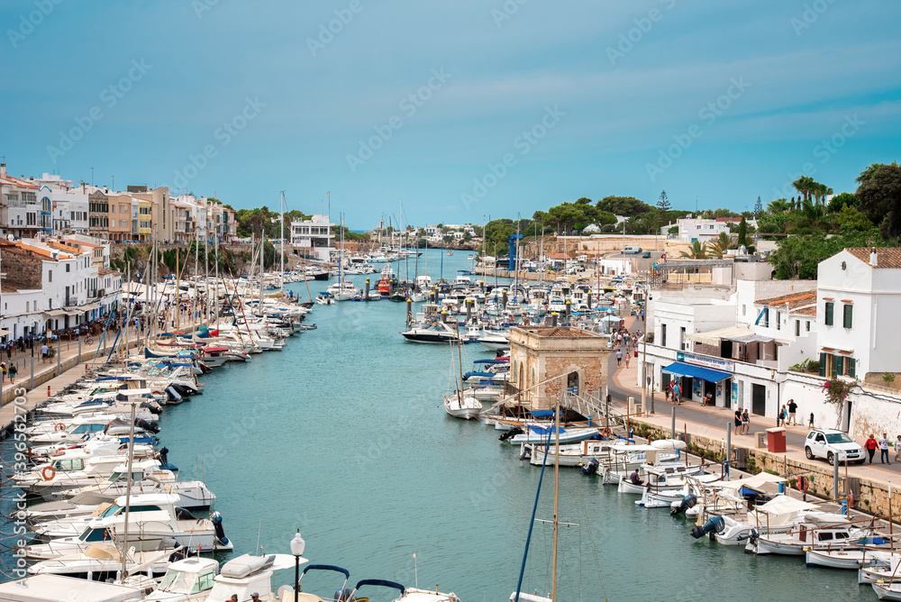 Menorca, Balearic Islands, Spain, 08.13.2019. Busy street in Menorca. Tourism in Spain. Boats in the bay. Balearic Islands during a summer period.