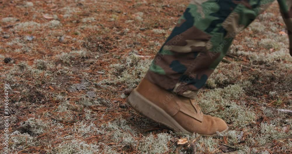 Closeup of a military shoe walking on the autumn undergrowth.