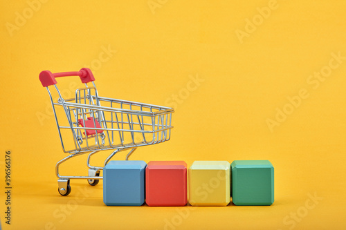 empty wooden cubes mockup style, copy space with shopping trolleys on yellow background. Colourful blocks template for creative design, place for text