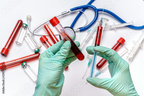 lab technician assistant holding syringe and test tube over light grey or white background with medical ampoule vials, syringes and stethoscope