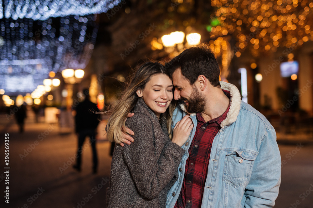 Young smiling couple having fun during the winter holidays on the street.