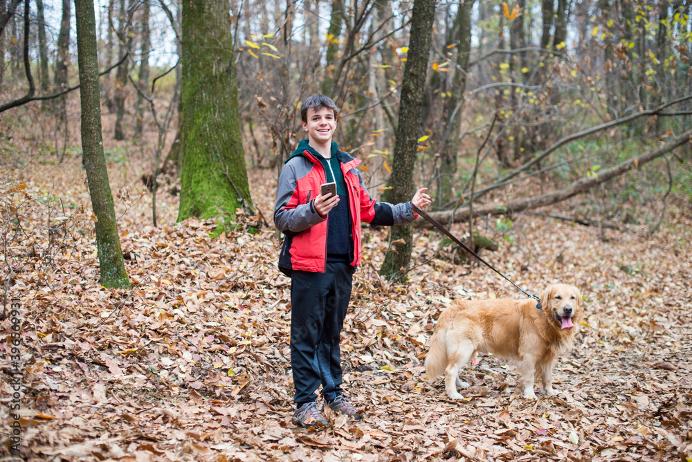 teenager walking in the forest with dog and smartphone in hand