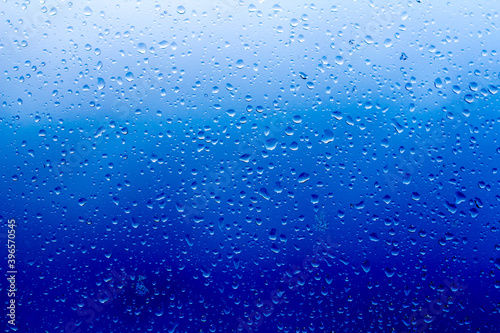 abstract background, raindrops on the glass against the blue stormy sky