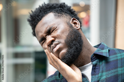 African man with toothache; portrait of black man suffering from toothache pain, tooth decay, tooth sensitivity; girl oral health care, dental care concept; african 20s adult man model