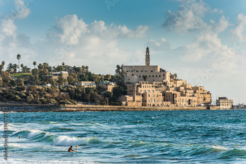 Old Jaffa city, old port and coastal line of Tel Aviv under sunset and lots of tourists are swimming and surfing at the Mediterranean sea. photo