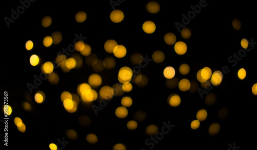 Bokeh on a black background for use in the photo editor. Beautiful bright curly bokeh. Magic background for new year and Christmas. Banner with yellow unfocused lights garlands in the form of circles.
