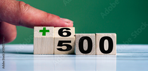 Hand turn wooden block with word 500+ and change to 600+ (Polish government assistance program
