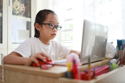 Portrait of 11-year-old teenager Asian girl using laptop for online study during homeschooling at home photo