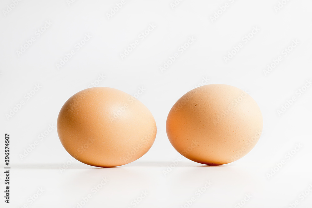 Two brown organic fresh raw eggs. Cut out and isolated on white background with soft shadows for added dimension. Two brown organic fresh raw eggs. Cut out and isolated on white background with soft shadows for added dimension.