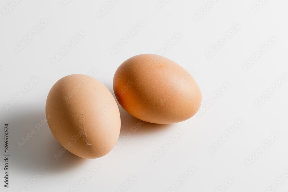 Two brown organic fresh raw eggs. Cut out and isolated on white background with soft shadows for added dimension. Two brown organic fresh raw eggs. Cut out and isolated on white background with soft shadows for added dimension.