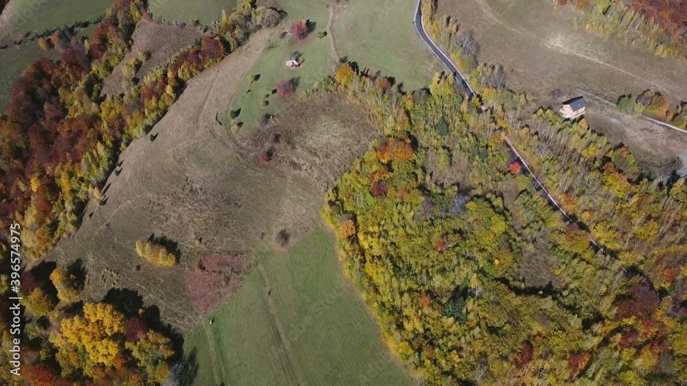 Aerial view revealing a countryside road with scattered houses on the hills in the autumn in the Apuseni region of Transylvania, Romania