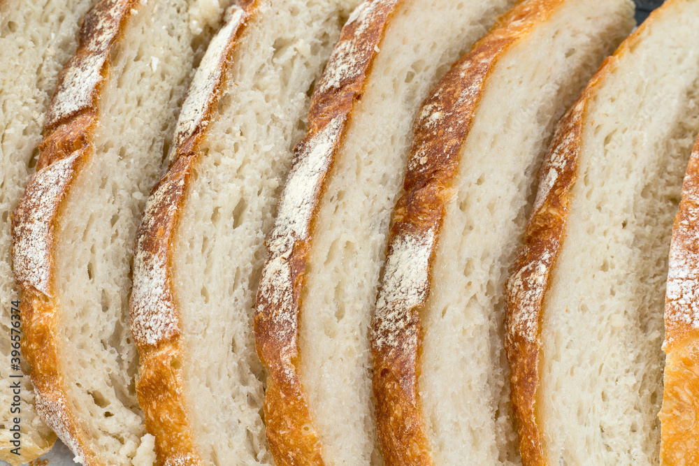 Freshly homemade bread sliced on a baking paper in a baking tray, light and airy inside with a crunchy rustic crust.