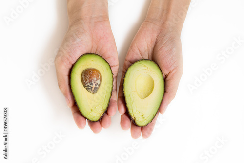 Close-Up Of  Female Hands Holding Avocado Against White Background