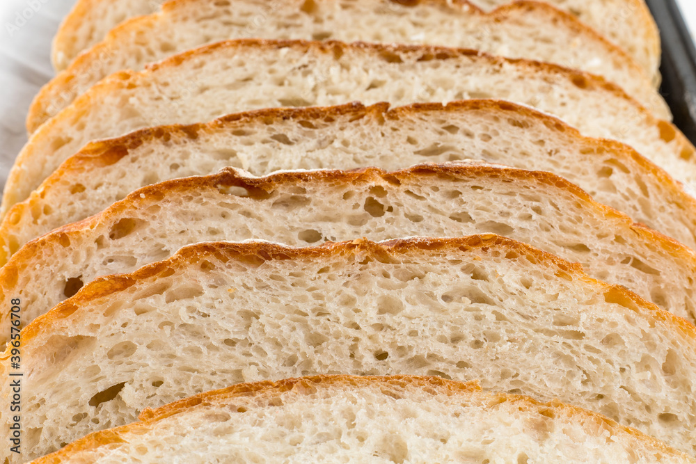 Freshly homemade bread sliced on a baking paper in a baking tray, light and airy inside with a crunchy rustic crust. Freshly homemade bread sliced on a baking paper in a baking tray, light and airy inside with a crunchy rustic crust.