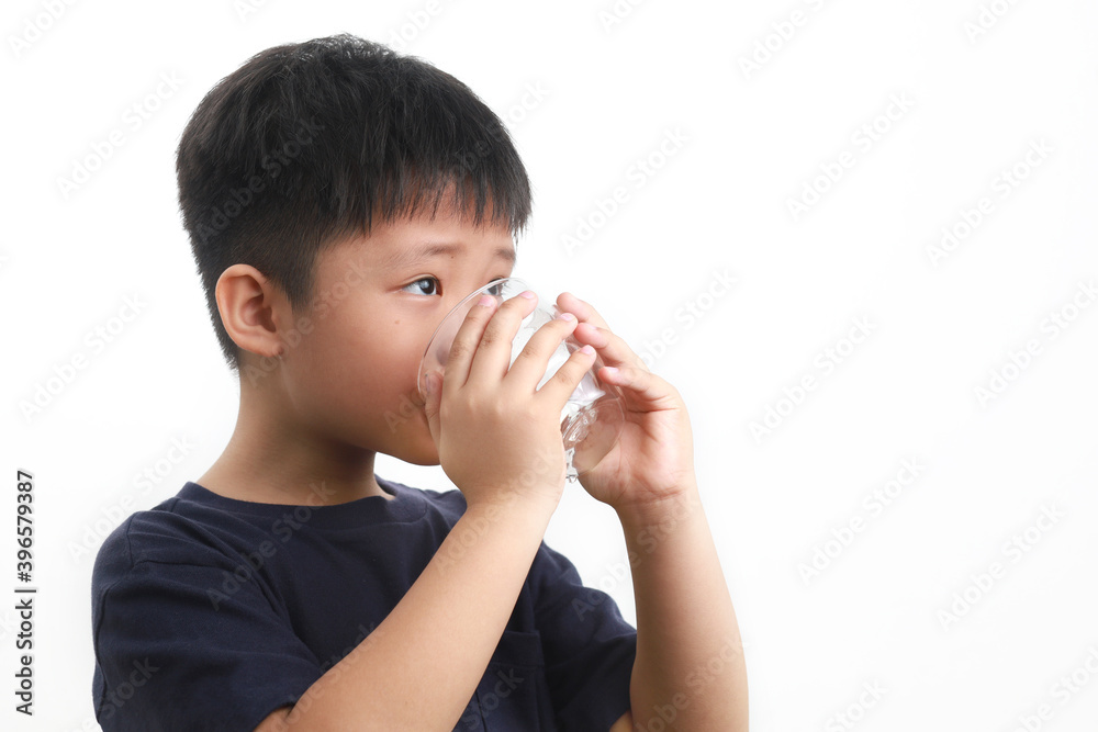 Young Asian boy drinking a glass of water, standing against a white background. Young Asian boy drinking a glass of water, standing against a white background.