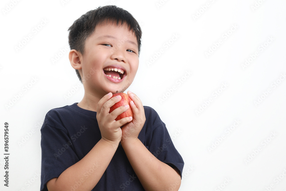 Portrait of a 9-year-old Asian Boy eating apple against a white background Portrait of a 9-year-old Asian Boy eating apple against a white background