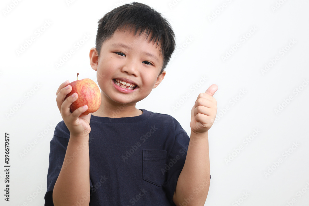 Portrait of a 9-year-old Asian Boy eating apple against a white background