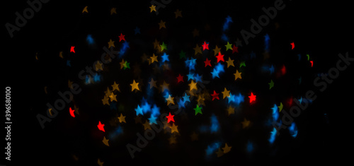 Bokeh on a black background for use in the photo editor. Beautiful bright curly bokeh. Magic background for new year and Christmas. Banner with unfocused lights garlands in form of Christmas tree.