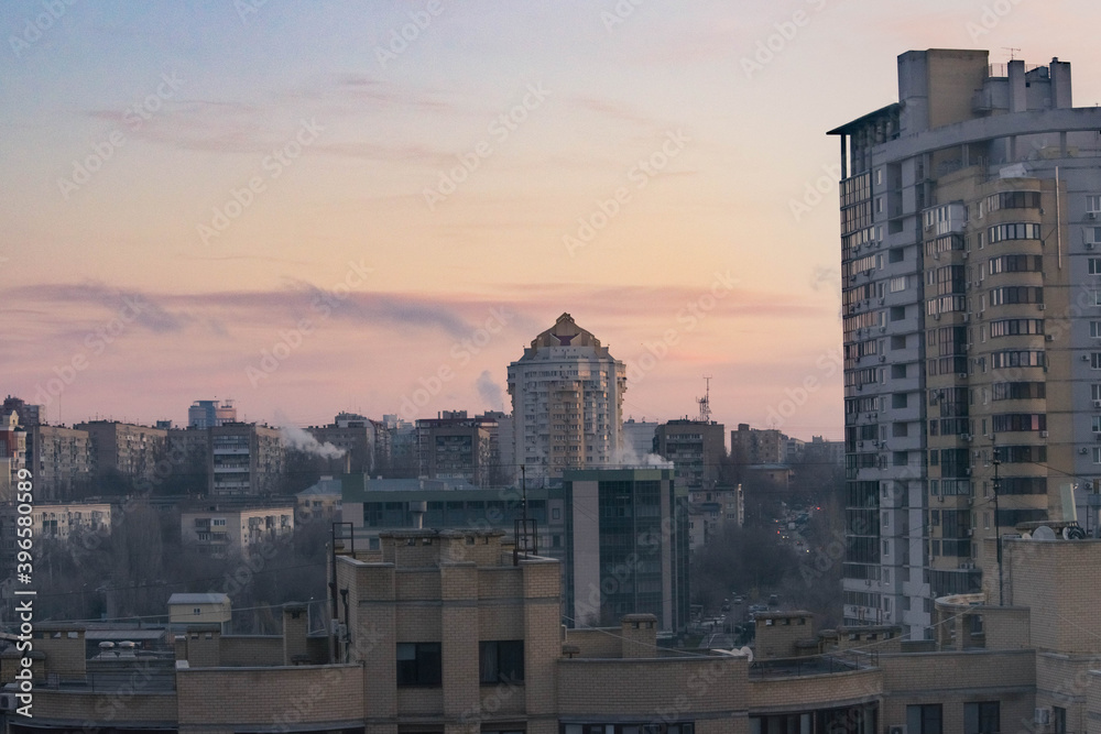 Panorama of the city. Houses against the background of a pink cloudy dawn sky.