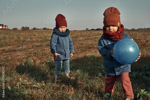 Twins play ball in the field, a lighthouse in the background, children two years old. Autumn walks in nature