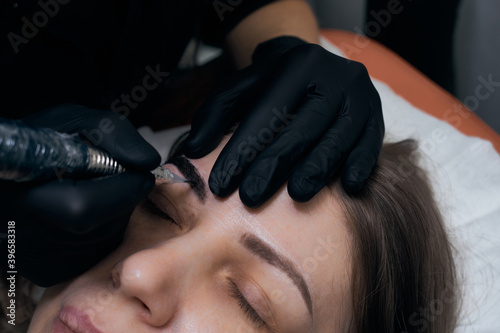 Permanent eyebrow makeup procedure. Eyebrow tattooing  process. The use of tools by a master for permanent eyebrow makeup.